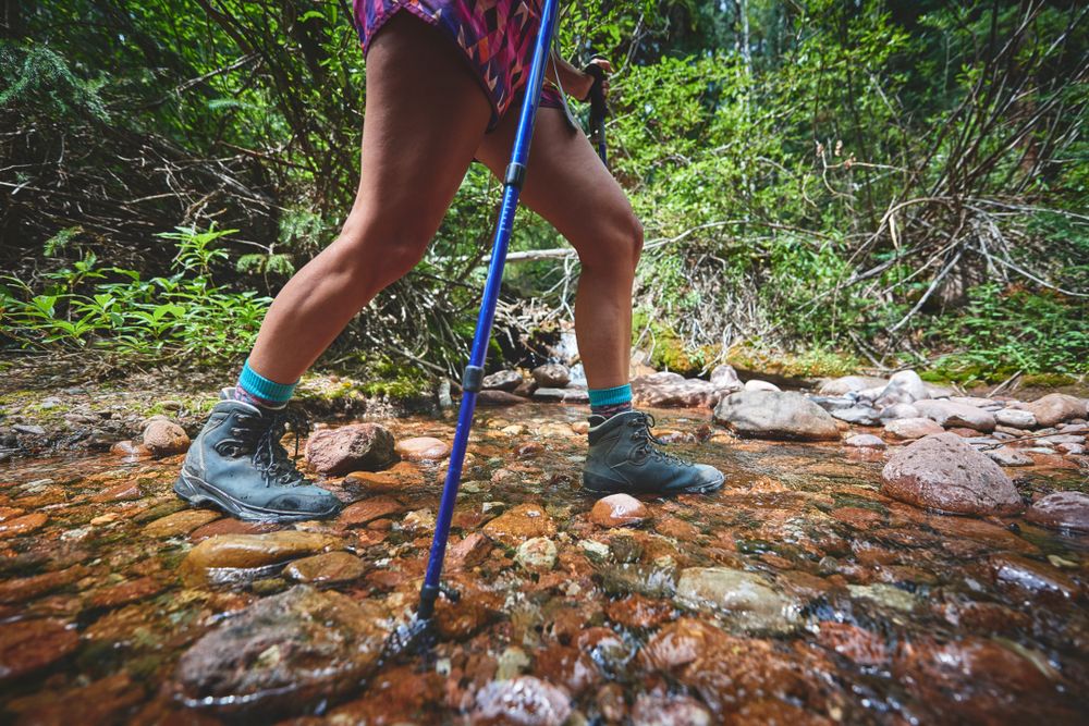 woman hiking through creek
